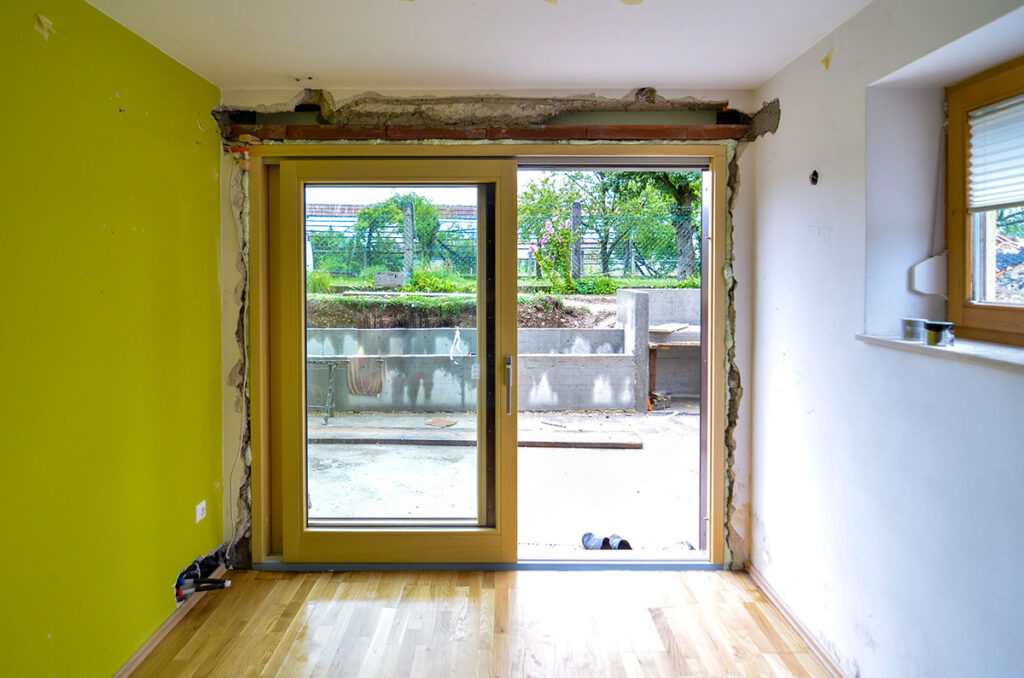 Replacing brick wall with glass sliding door in home requires a contractor.