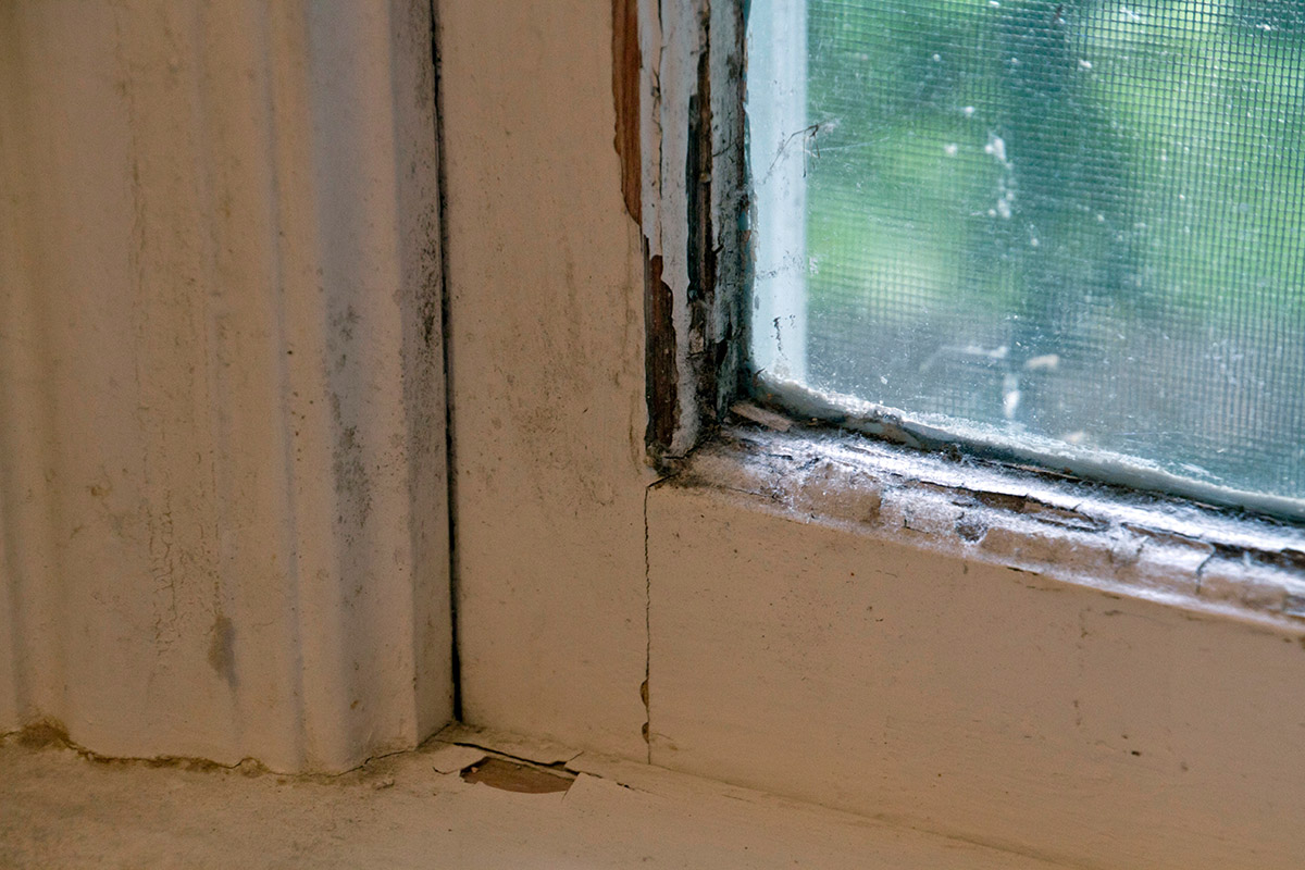 The damaged, weathered wood window frame needs to be replaced.